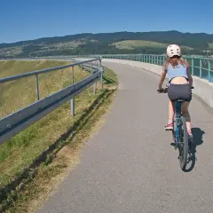 Dziewczynka na rowerze przemierza malowniczą czorsztyńską trasę rowerową wzdłuż jeziora.