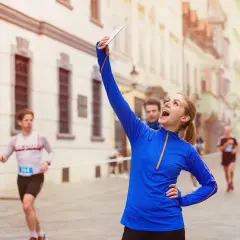 Radosna biegaczka robi selfie podczas biegu ulicznego. To świetny sposób, by zacząć bieganie i uwiecznić swoje sukcesy!