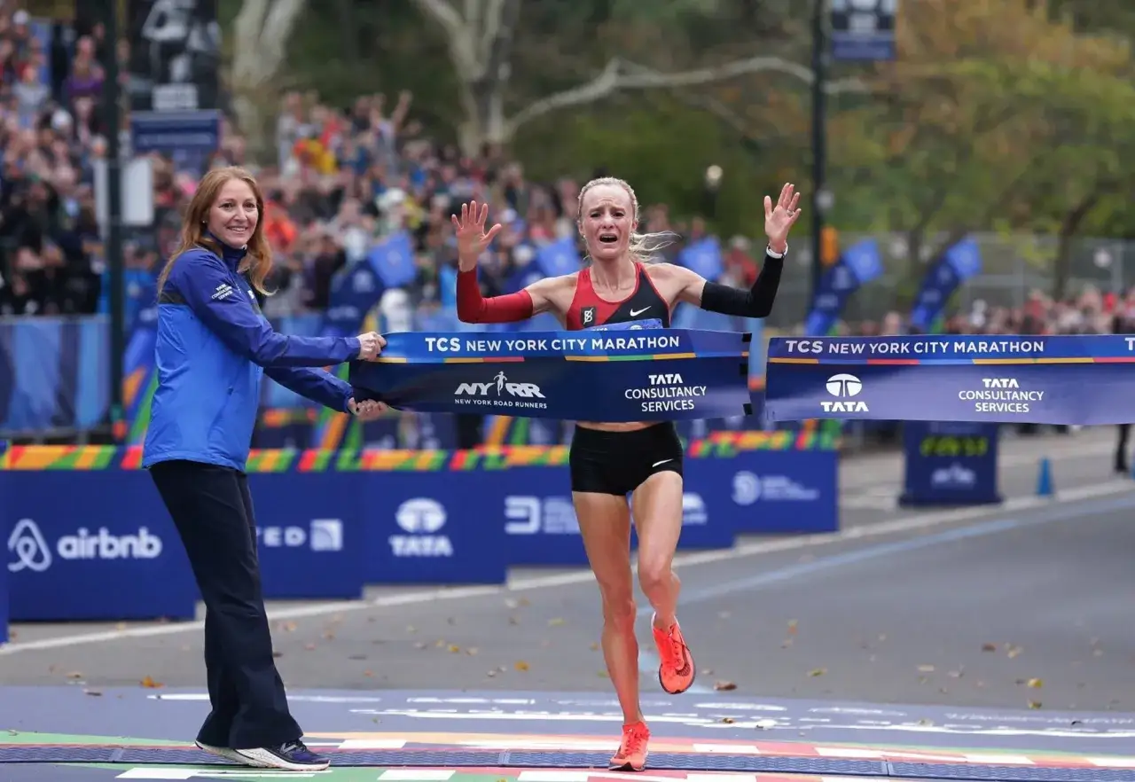 Kobieta przekracza metę maratonu, który ma 42,195 kilometra. Radość na jej twarzy po pokonaniu tego dystansu.